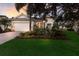 Charming single-story home featuring a manicured lawn, paver driveway, and lush landscaping with elegant exterior lighting at 13848 American Prairie Pl, Lakewood Ranch, FL 34211