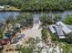 Aerial view of a waterfront property featuring a boat ramp, dock, and colorful kayaks, nestled among mature trees at 14314 17Th E Ct, Parrish, FL 34219