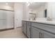 Beautiful bathroom with dual sinks, gray cabinets, quartz countertop, and a glass-enclosed shower at 14314 17Th E Ct, Parrish, FL 34219
