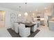 Elegant dining area with modern lighting fixtures, white upholstered chairs, and view to kitchen at 14314 17Th E Ct, Parrish, FL 34219
