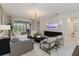 Bright living room with gray sectional sofa, large windows, and a mounted television at 14314 17Th E Ct, Parrish, FL 34219