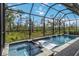 A luxurious screened-in pool and spa with waterfall features and a beautiful view of the natural surroundings at 14314 17Th E Ct, Parrish, FL 34219
