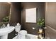 Stylish powder room features pedestal sink, white toilet, dark walls and gold accents at 14314 17Th E Ct, Parrish, FL 34219