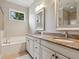 Elegant bathroom boasting a soaking tub, double vanity with granite countertops, modern fixtures, and natural light at 14325 Stirling Dr, Lakewood Ranch, FL 34202