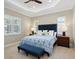 Comfortable bedroom with tray ceiling, shuttered windows, and blue upholstered headboard and bench at 14325 Stirling Dr, Lakewood Ranch, FL 34202