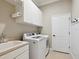 Functional laundry room with white cabinets, a sink, and modern washer and dryer units at 14325 Stirling Dr, Lakewood Ranch, FL 34202