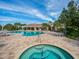 Inviting pool area featuring a hot tub, swimming pool, lounge chairs, tables, and a building in the background at 14325 Stirling Dr, Lakewood Ranch, FL 34202