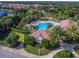 Aerial view of a community pool area with lounge chairs, umbrellas, palm trees, and a clubhouse with a tile roof at 14325 Stirling Dr, Lakewood Ranch, FL 34202