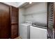 Functional laundry room featuring appliances, storage, and a louvered door at 15718 Squirrel Tree Pl, Tampa, FL 33624