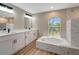 A spacious bathroom with double sink vanity, soaking tub and window with palm tree view at 168 Wading Bird Dr, Venice, FL 34292