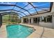 Inviting screened-in pool with steps and a view of the home's exterior and summer kitchen at 168 Wading Bird Dr, Venice, FL 34292