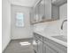Well-lit laundry room features gray shaker cabinets, white counters, a sink, and tile flooring at 17719 Palmiste Dr, Bradenton, FL 34202