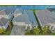 Aerial view of a modern home boasting a gray roof, paver driveway, and a well-manicured lawn, complemented by serene water views at 17811 Roost Pl, Bradenton, FL 34211