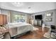 Bright main bedroom with wood floors, a comfortable bed, a television, and views of the backyard pool area at 1809 Buccaneer Ter, Sarasota, FL 34231
