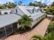 Aerial view showcasing the house, its metal roof, brick driveway, landscaping, and neighborhood at 1841 Datura St, Sarasota, FL 34239