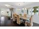 Open-concept dining room featuring dark wood floors, wicker chairs, and elegant chandelier lighting at 1841 Datura St, Sarasota, FL 34239