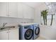 Well-lit laundry room with modern washer and dryer, plus ample storage cabinets and a utility sink at 1841 Datura St, Sarasota, FL 34239
