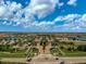 An aerial view shows the community entrance with its manicured landscaping and palm-lined streets at 20542 Trattoria Loop, Venice, FL 34293