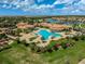 A stunning aerial view of the pool and clubhouse on a sunny day with palm trees and beautiful landscaping at 20542 Trattoria Loop, Venice, FL 34293
