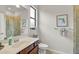 Bright bathroom with a glass-enclosed shower, a vanity with dark brown cabinets, and a window at 20542 Trattoria Loop, Venice, FL 34293