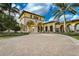 Wide angle view of a community clubhouse entrance with brick paving, stone columns, and lush landscaping at 20542 Trattoria Loop, Venice, FL 34293