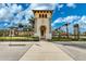 View of a community center entrance with stone columns, archways, palm trees, and a playground on the right at 20542 Trattoria Loop, Venice, FL 34293
