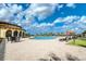 Exterior view of a community pool area with lounge chairs and tables, surrounded by lush landscaping and blue skies at 20542 Trattoria Loop, Venice, FL 34293