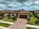 Aerial view of charming home featuring a tile roof, paver driveway and manicured landscaping at 20542 Trattoria Loop, Venice, FL 34293