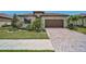 Inviting home exterior showcasing a brick paver driveway, tropical landscaping and a two-car garage at 20542 Trattoria Loop, Venice, FL 34293