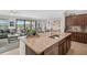 A granite kitchen island with a sink overlooks the living room in an open concept layout at 20542 Trattoria Loop, Venice, FL 34293