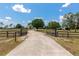 Long driveway leading to a beautiful home, framed by an ornate gate and lush greenery on either side at 22803 67Th E Ave, Bradenton, FL 34211