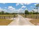 Long driveway leads to a beautiful home with an ornate gate and scenic views of the surrounding property at 22803 67Th E Ave, Bradenton, FL 34211