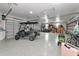 Spacious three car garage featuring speckled epoxy flooring and ample storage, including overhead racks and wall shelving at 22803 67Th E Ave, Bradenton, FL 34211