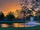 Picturesque pond with fountain reflecting the sunset's golden hues, bordered by mature trees at 22803 67Th E Ave, Bradenton, FL 34211