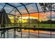 Covered pool reflecting the vibrant colors of the sunset, surrounded by greenery, for a tranquil ambiance at 22803 67Th E Ave, Bradenton, FL 34211