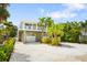 Inviting two-story home with a balcony, well-manicured landscaping, and a white gravel driveway at 229 S Harbor Dr, Holmes Beach, FL 34217