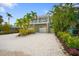 Beautiful two-story home with lush landscaping, white gravel driveway, and a covered balcony at 229 S Harbor Dr, Holmes Beach, FL 34217
