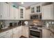 Close up of a kitchen with stone countertops, stainless steel appliances, and custom cabinetry with decorative glass at 229 S Harbor Dr, Holmes Beach, FL 34217