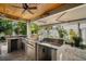 Well-equipped outdoor kitchen with stainless steel appliances, granite countertops, and a custom-built grill at 229 S Harbor Dr, Holmes Beach, FL 34217