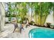 Relaxing outdoor patio area with woven chairs, lush landscaping, and poolside views at 229 S Harbor Dr, Holmes Beach, FL 34217