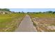 Wide concrete walkway through the flat green space behind the property at 2607 Lancaster Dr # 35, Sun City Center, FL 33573