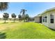 Expansive backyard with lush green lawn, mature palm trees, and screened-in lanai at 315 Heritage Isles Way, Bradenton, FL 34212