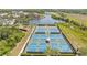 Aerial view of multiple tennis courts with blue surfaces, surrounded by lush landscaping and water views at 315 Heritage Isles Way, Bradenton, FL 34212