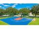 Community basketball court with blue and red painted surface, set among mature trees at 3303 Pine Top Dr, Valrico, FL 33594