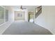 Bright living room with neutral carpet, ceiling fan, staircase, and ample natural light from large windows at 3303 Pine Top Dr, Valrico, FL 33594