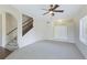 Spacious living room featuring carpet, a ceiling fan, a staircase, and an inviting entryway with double doors at 3303 Pine Top Dr, Valrico, FL 33594