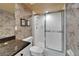 Well-lit bathroom with a glass shower, a vanity featuring dark granite countertops, and floral wallpaper at 3540 Gulf Of Mexico Dr # 303, Longboat Key, FL 34228