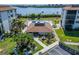 Aerial view of a clubhouse with a pool, lush landscaping, and a parking area at 3540 Gulf Of Mexico Dr # 303, Longboat Key, FL 34228