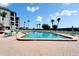 Community swimming pool area with lounge chairs and lush tropical landscaping and blue skies at 3540 Gulf Of Mexico Dr # 303, Longboat Key, FL 34228