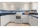 Kitchen featuring white cabinets, modern appliances, and blue backsplash accents at 3627 Longmeadow # 39, Sarasota, FL 34235